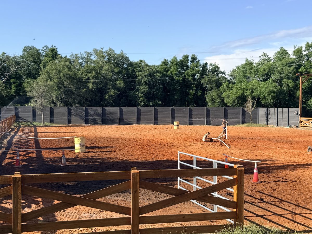 Riding arena with wood rail fencing and graded footing